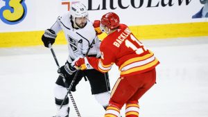 Los Angeles Kings forward Phillip Danault (24) is checked by Calgary Flames forward Mikael Backlund (11) during first period NHL hockey action in Calgary, Tuesday, Feb. 27, 2024. (Jeff McIntosh/CP)