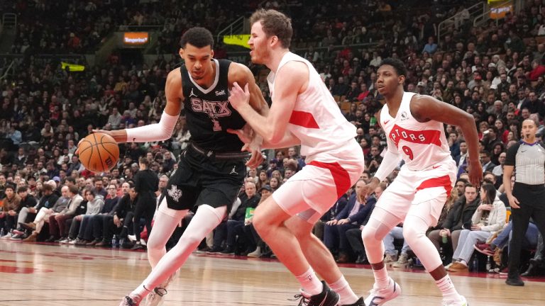 San Antonio Spurs' Victor Wembanyama, left, drives at Toronto Raptors' Jakob Poeltl as Raptors' RJ Barrett, right, as looks on during first half NBA basketball action in Toronto on Monday, February 12, 2024. (Chris Young/CP)