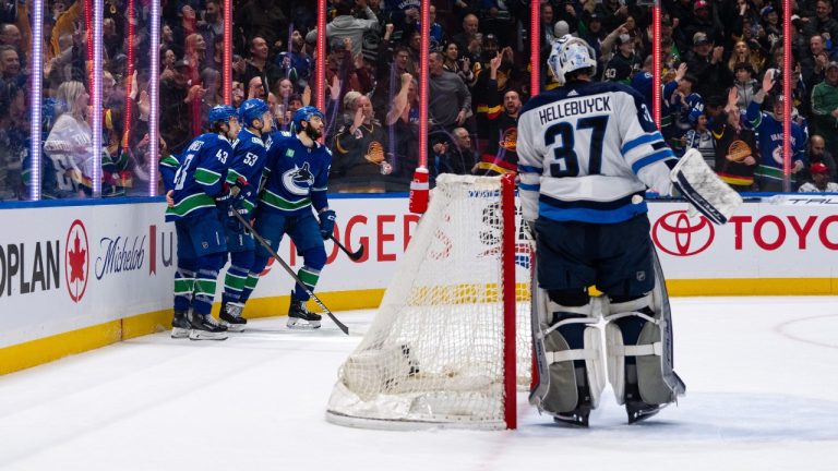 Vancouver Canucks' Quinn Hughes (43), Teddy Blueger (53) and Phillip Di Giuseppe (34) skate to the bench after celebrating Di Giuseppe's goal as Winnipeg Jets goaltender Connor Hellebuyck (37) watches during the first period of an NHL game, in Vancouver, Saturday, March 9, 2024. (Ethan Cairns/CP)