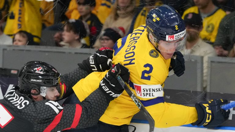 Canada's Matthew Poitras (15) checks Sweden's Elias Pettersson (2) into the boards during second period hockey action at the IIHF World Junior Hockey Championship in Gothenburg, Sweden, Friday, Dec. 29, 2023. (Christinne Muschi/CP)