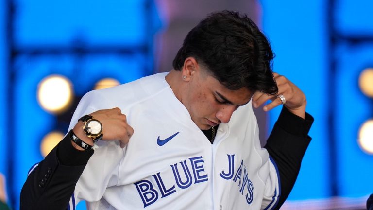 Brandon Barriera puts on a jersey after being selected by the Toronto Blue Jays with the 23rd pick of the 2022 MLB baseball draft, Sunday, July 17, 2022, in Los Angeles. (Jae C. Hong/AP Photo)