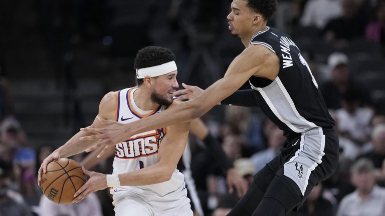 Phoenix Suns guard Devin Booker, left, is defended by San Antonio Spurs center Victor Wembanyama, right, during the second half of an NBA basketball game in San Antonio, Saturday, March 23, 2024. (Eric Gay/AP)