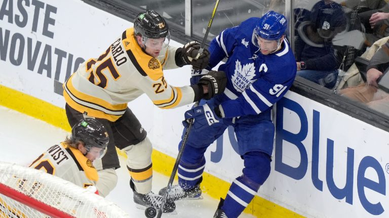 Boston Bruins defenseman Brandon Carlo (25) and Toronto Maple Leafs center John Tavares (91) vie for control of the puck in front of forward Jesper Boqvist (70), left, in the second period of an NHL hockey game, Thursday, March 7, 2024, in Boston. (Steven Senne/AP)