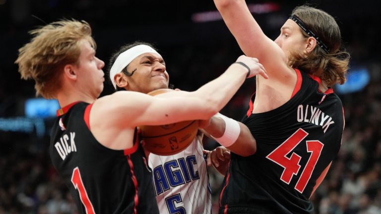 Orlando Magic forward Paolo Banchero (5) tries to drive between Toronto Raptors guard Gradey Dick (1) and teammate Kelly Olynyk (41) during second half NBA basketball in Toronto, Friday, March 15, 2024. (Frank Gunn/CP)