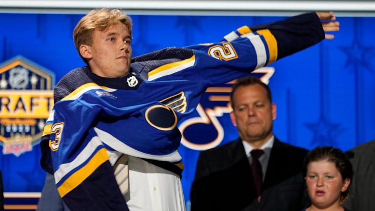 Theo Lindstein puts on a St. Louis Blues jersey after being picked by the team during the first round of the NHL hockey draft Wednesday, June 28, 2023, in Nashville, Tenn. (George Walker IV/AP)