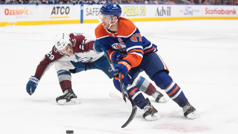 Colorado Avalanche's Nathan MacKinnon (29) and Edmonton Oilers' Connor McDavid (97) battle for the puck during overtime NHL action in Edmonton, Saturday, March 16, 2024. (Jason Franson/CP)