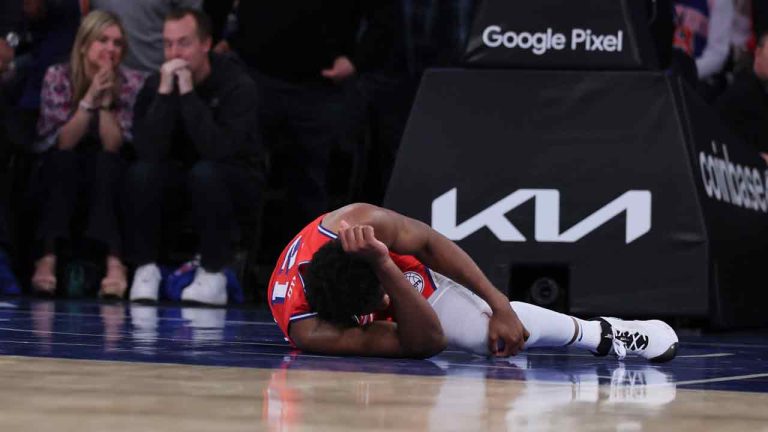 Philadelphia 76ers center Joel Embiid (21) remains on the court during the first half in Game 1 of the team's NBA basketball first-round playoff series against the Philadelphia 76ers on Saturday. April 20, 2024, in New York. Embiid had the ball in the lane, threw it off the backboard to pass it to himself, rose up and slammed it down. But he immediately grabbed at his left knee after landing and fell to the court. (J. Conrad Williams Jr./Newsday via AP)