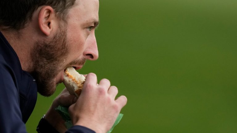 A patron eats a pimento cheese sandwich during a practice round in preparation for the Masters golf tournament at Augusta National Golf Club. (Charlie Riedel/AP)