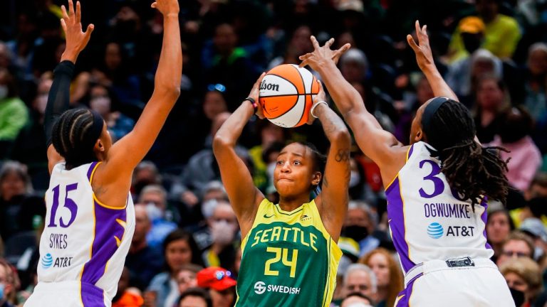 Seattle Storm guard Jewell Loyd passes the ball between Los Angeles Sparks guard Brittney Sykes and forward Nneka Ogwumike during the second quarter of a WNBA basketball game Friday, May 20, 2022, in Seattle. (Jennifer Buchanan/The Seattle Times via AP)