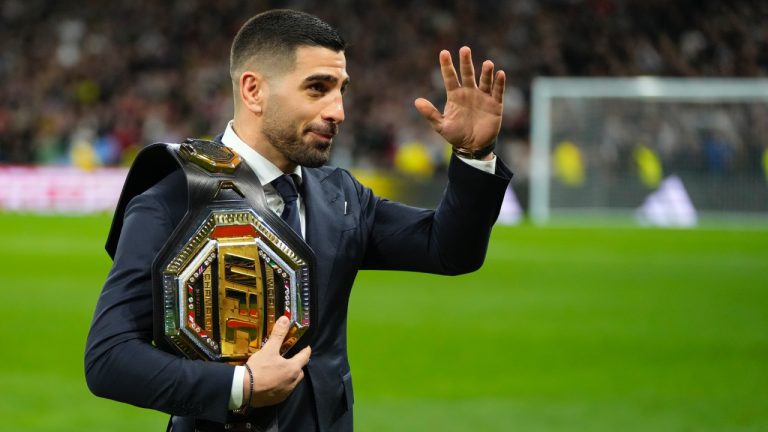 UFC featherweight world champion Ilia Topuria waves to fans as he leaves the pitch after taking the honorary kickoff ahead of the Spanish La Liga soccer match between Real Madrid and Sevilla at the Santiago Bernabeu stadium in Madrid, Spain on Feb. 25, 2024. (Manu Fernandez/AP)