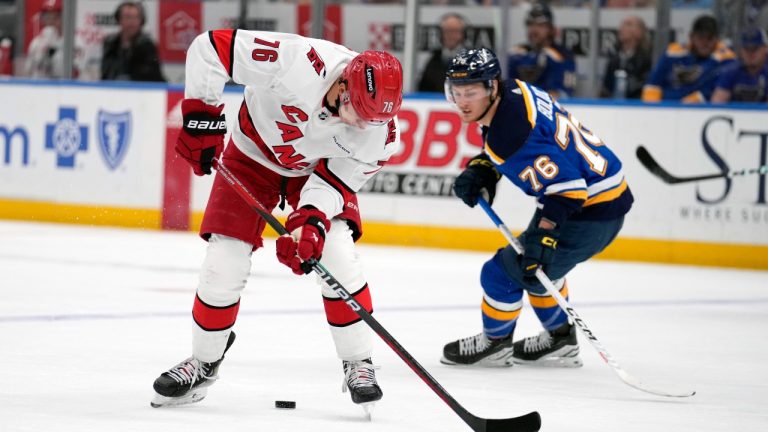 Carolina Hurricanes' Brady Skjei, left, skates over the puck as St. Louis Blues' Zack Bolduc, right, defends during the first period of an NHL hockey game Friday, April 12, 2024, in St. Louis. (Jeff Roberson/AP Photo)