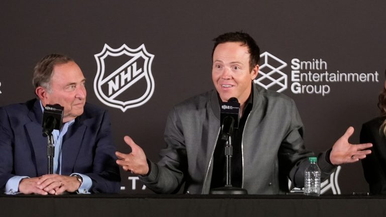 NHL commissioner Gary Bettman, left, listens to Ryan Smith, co-founder and chairman of Smith Entertainment Group, speak during a news conference Friday, April 19, 2024, in Salt Lake City about the moved of the Arizona Coyotes franchise to Utah. (Rick Bowmer/AP Photo)