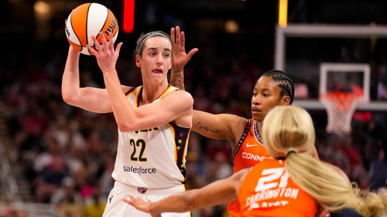 Indiana Fever guard Caitlin Clark (22) looks to pass over Connecticut Sun guard Tyasha Harris (52) and guard DiJonai Carrington (21) in the second half of a WNBA basketball game in Indianapolis, Monday, May 20, 2024. (Michael Conroy/AP)