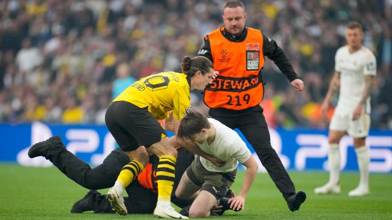 Dortmund's Marcel Sabitzer tries to hold up a pitch invader followed by security during the Champions League final soccer match between Borussia Dortmund and Real Madrid at Wembley stadium in London, Saturday, June 1, 2024. (AP Photo/Kin Cheung)