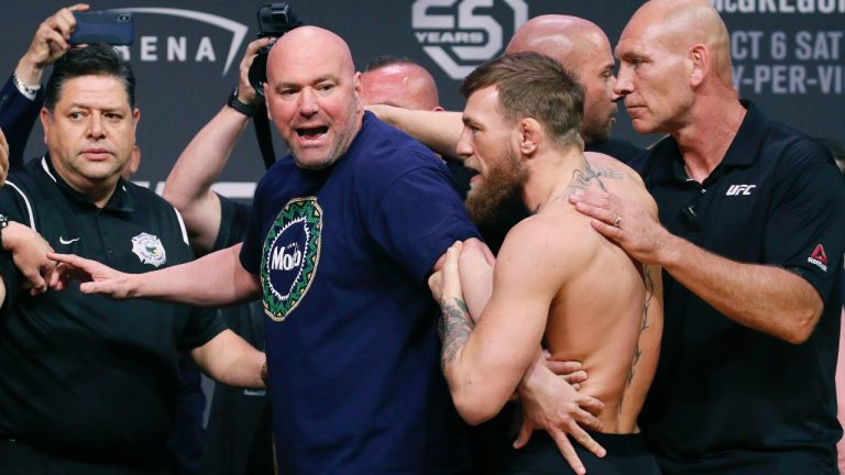 Dana White holds back Conor McGregor from his opponent during a ceremonial UFC weigh-in in Las Vegas. (John Locher/AP)