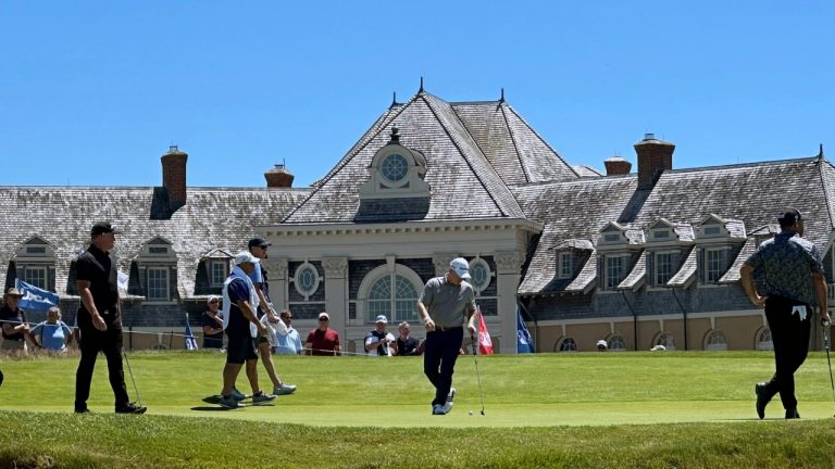 Frank Bensel, center, plays on the 18th green in front of the Newport Country Club clubhouse during the U.S. Senior Open tournament in Newport, R.I., June 28, 2024. (AP Photo/Chris Lehourites)