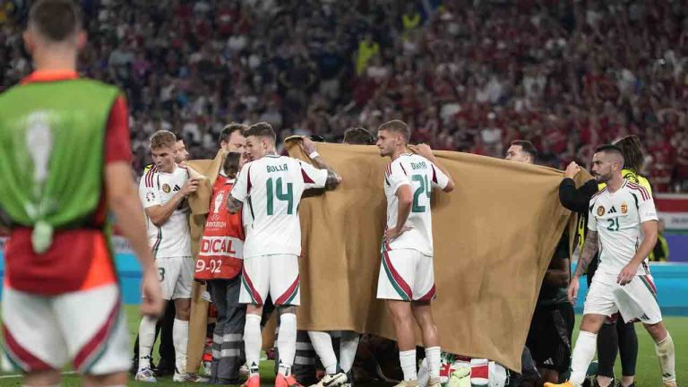 Players hold a blanket as medical personnel treat Hungary's Barnabas Varga during a Group A match between Scotland and Hungary at the Euro 2024 soccer tournament in Stuttgart, Germany, Sunday, June 23, 2024. (Antonio Calanni/AP)