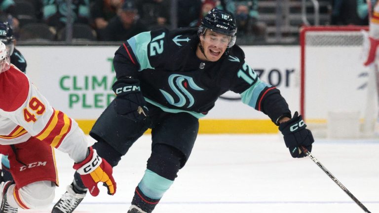 Calgary Flames forward Jakob Pelletier (49) carries the puck as Seattle Kraken forward Andrew Poturalski pursues during the third period of a preseason NHL hockey game Tuesday, Sept. 27, 2022, in Seattle. (AP/Jason Redmond)