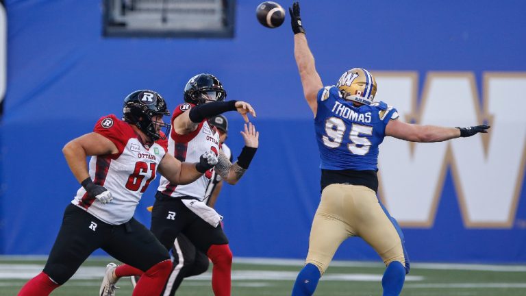 Ottawa Redblacks quarterback Dru Brown's (3) pass gets knocked down by Winnipeg Blue Bombers' Jake Thomas (95) during first half CFL action in Winnipeg Friday, July 5, 2024. (John Woods/CP)