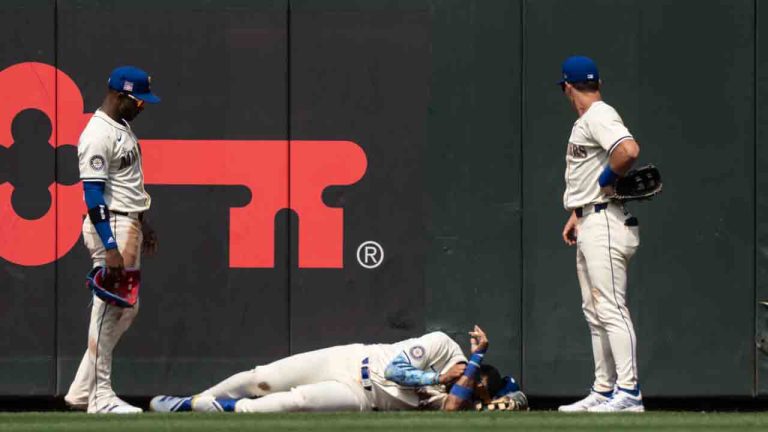 Seattle Mariners Julio Rodriguez, centre, lies on the ground between right fielder Victor Robles, left, and left fielder Dylan Moore after crashing into the outfield wall during the eighth inning of a baseball game against the Houston Astros, Sunday, July 21, 2024, in Seattle. (Stephen Brashear/AP)