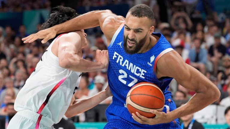 France's Rudy Gobert, right, hits Japan's Hirotaka Yoshii in the head as he drives toward the basket in a men's basketball game at the 2024 Summer Olympics, Tuesday, July 30, 2024, in Villeneuve-d'Ascq, France. Gobert was called for an offensive foul on the play. (AP Photo/Michael Conroy)