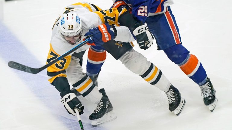 New York Islanders center Brock Nelson (29) defends Pittsburgh Penguins defenseman Pierre-Olivier Joseph (73) as seen through the glass during the third period of an NHL hockey game, Sunday, Feb. 28, 2021, in Uniondale, N.Y. (AP Photo/Kathy Willens)