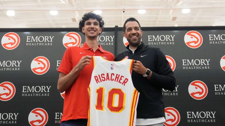 Atlanta Hawks' Zaccharie Risacher, left, and General Manager Landry Fields, right, hold up Risacher's jersey after a news conference, June 28, 2024. (AP Photo/Brynn Anderson)