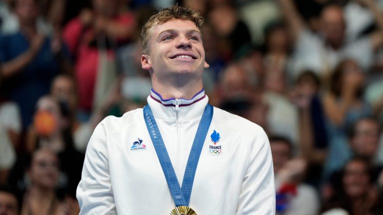 Gold medalist Leon Marchand smiles while standing on the winner's podium following the men's 200-meter breaststroke final at the 2024 Summer Olympics, Wednesday, July 31, 2024, in Nanterre, France. (Matthias Schrader/AP)