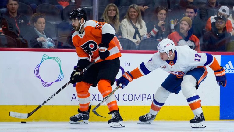 Philadelphia Flyers' Tanner Laczynski, left, tries to keep the puck away from New York Islanders' Matt Martin during the second period of an NHL hockey game, Tuesday, Nov. 29, 2022, in Philadelphia. (Matt Slocum/AP Photo)