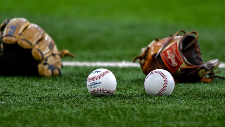 Baseballs and gloves sit on the field. (AP Photo/Albert Pena)