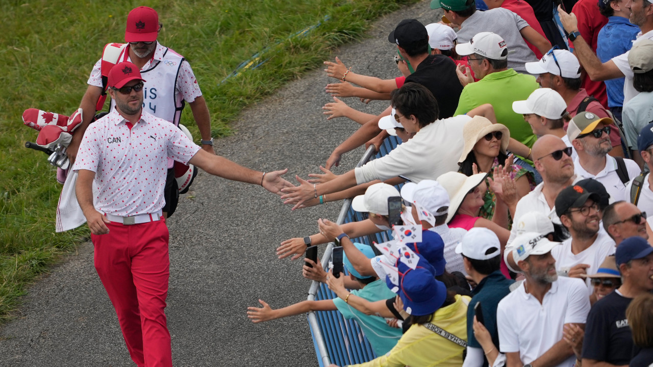 Corey Conners, of Canada, taps fans hands as he walks to the 1st tee during the final round of the men's golf at the 2024 Summer Olympics, Sunday, Aug. 4, 2024, at Le Golf National in Saint-Quentin-en-Yvelines, France. (Matt York/AP) 