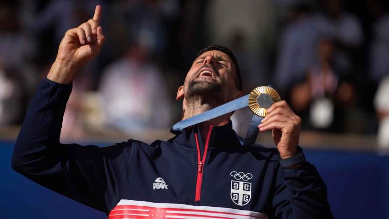 Serbia's Novak Djokovic shows his gold medal after defeating Spain's Carlos Alcaraz in the men's singles tennis final at the Roland Garros stadium during the 2024 Summer Olympics. (Louise Delmotte/AP)