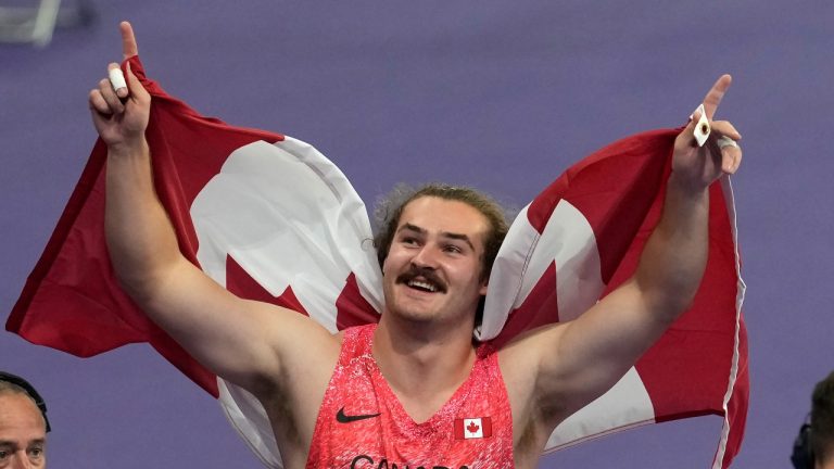 Ethan Katzberg, of Nanaimo, B.C., celebrates after winning gold in the men's hammer throw event at the 2024 Summer Olympics, Sunday, Aug. 4, 2024, in Saint-Denis, France. (Adrian Wyld/CP Photo)