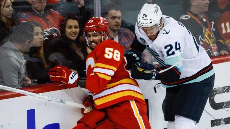 Seattle Kraken defenceman Jamie Oleksiak (24) checks Calgary Flames defenceman Oliver Kylington (58) during second period NHL hockey action in Calgary, Monday, March 4, 2024. (Jeff McIntosh/CP)