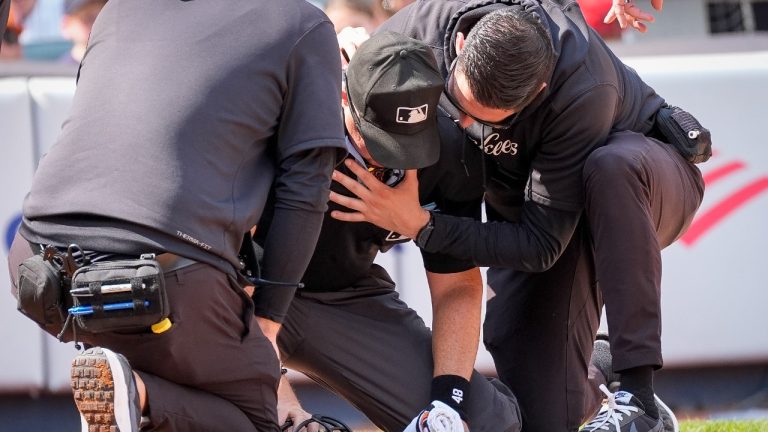 Medical staff tend to umpire Nick Mahrley, centre, after he was hit by a bat during the fifth inning of a baseball game between the Colorado Rockies and the New York Yankees, Sunday, Aug. 25, 2024, in New York. (Bryan Woolston/AP)