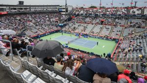 People sit with umbrellas on centre court during a rain stoppage ahead of the second round match between Thanasi Kokkinakis of Australia and Hubert Hurkacz of Poland at the National Bank Open tennis tournament in Montreal, Thursday, August 8, 2024. (Graham Hughes/CP)