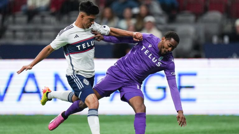 Vancouver Whitecaps' Mathias Laborda, left, shoves Pacific FC's Reon Moore off the ball during the first half of a Canadian Championship semifinal soccer match, in Vancouver, on Tuesday, August 27, 2024. (Darryl Dyck/CP)