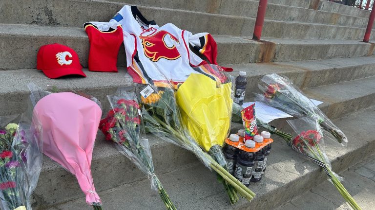 A fan-made memorial for Johnny Gaudreau, with flowers and Calgary Flames garments, is seen on the steps of the Saddledome. (Lauren Krugel/CP)