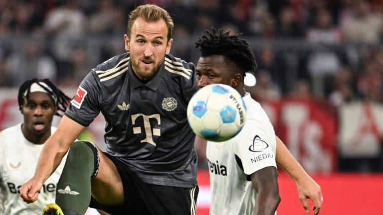 Munich's Harry Kane passes the ball past Leverkusen's Edmond Tapsoba during the German Bundesliga soccer match between Bayern Munich and Leverkusen at the Allianz Arena in Munich, Germany, Saturday, Sept. 28, 2024. (Lukas Barth-Tuttas/dpa via AP)