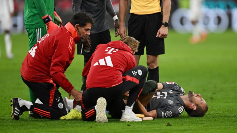 Munich's Harry Kane gets assistance as he lies on the pitch during the German Bundesliga soccer match between Bayern Munich and Leverkusen at the Allianz Arena in Munich, Germany, Saturday, Sept. 28, 2024. (Sven Hoppe/dpa via AP)