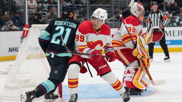 Calgary Flames defenseman Zayne Parekh (89) fights for position with Seattle Kraken centre Tucker Robertson (21) in front of goaltender Dustin Wolf (32) during the third period of a pre-season NHL hockey game Sunday, Sept. 22, 2024, in Seattle. (Jason Redmond/AP)