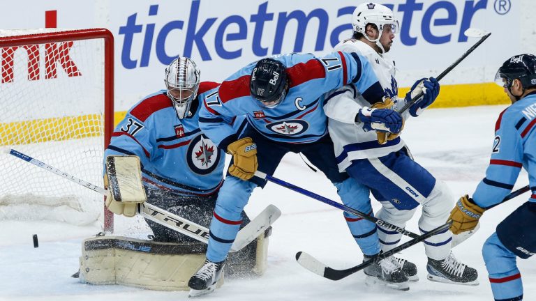 Winnipeg Jets goaltender Connor Hellebuyck (37) saves the shot as Adam Lowry (17) defends against Toronto Maple Leafs' Auston Matthews (34) during second period NHL action in Winnipeg on Saturday, January 27, 2024. (CP)