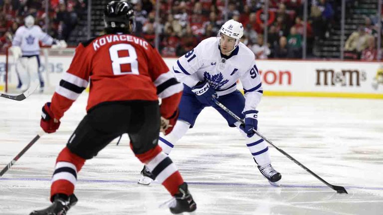 Toronto Maple Leafs centre John Tavares (91) looks to shoot around New Jersey Devils defenceman Johnathan Kovacevic (8) during the first period of an NHL hockey game Thursday, Oct. 10, 2024, in Newark, N.J. (Adam Hunger/AP)