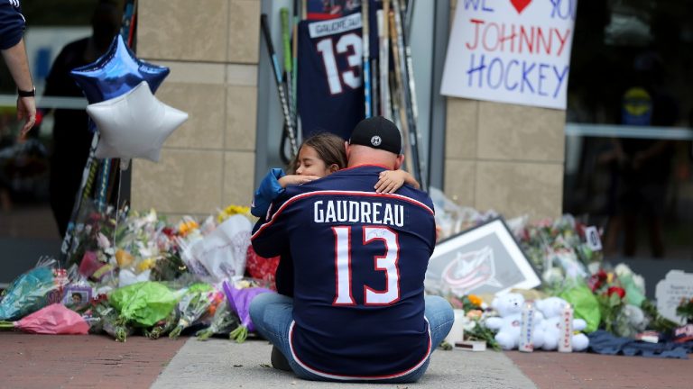 Shiloh Rivera, facing, mourns with Hylas Stemen of Columbus, at the makeshift memorial set up by fans for Blue Jackets hockey player Johnny Gaudreau in Columbus, Ohio, Friday, Aug. 30, 2024. Gaudreau, along with his brother Matthew, was fatally struck by a motorist while riding his bicycle on Thursday. (Joe Maiorana/AP)