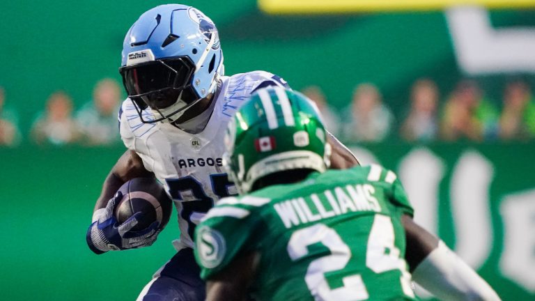 Toronto Argonauts' Ka'Deem Carey (25) runs against Saskatchewan Roughriders' Deontai Williams (24) during the second half of CFL football action in Regina, on Thursday, July 4, 2024. (Heywood Yu/CP)