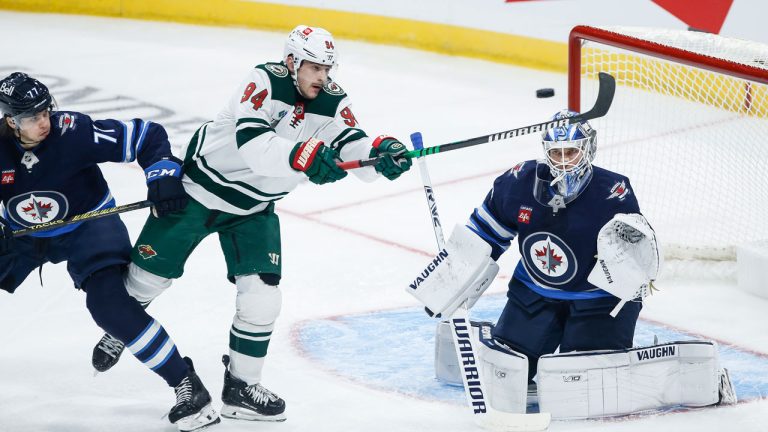 Winnipeg Jets' Tyrel Bauer (77) defends as Minnesota Wild's Jakub Lauko (94) attempts to tip the puck past Jets goaltender Kaapo Kahkonen (34) during first period NHL pre-season game action in Winnipeg. (John Woods/THE CANADIAN PRESS)