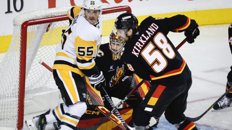 Pittsburgh Penguins' Noel Acciari, left, screens Calgary Flames goalie Dustin Wolf, centre, as Justin Kirkland defends during second period NHL hockey action in Calgary on Tuesday, Oct. 22, 2024. (Jeff McIntosh/CP)