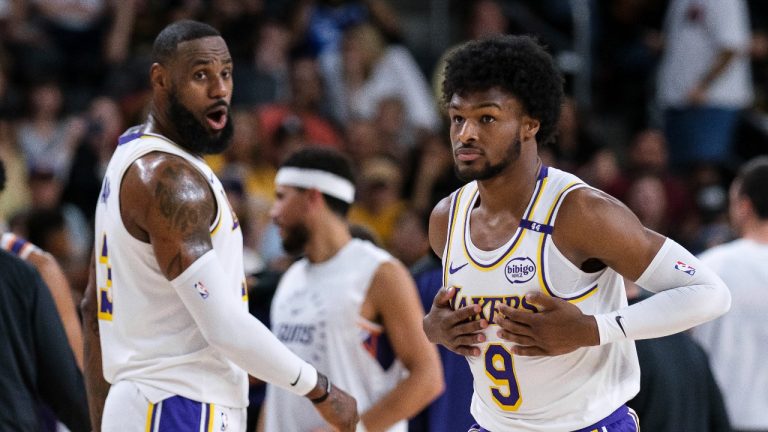 Los Angeles Lakers guard Bronny James (9), right, steps onto the court with Los Angeles Lakers forward LeBron James (23) during the first half of a preseason NBA basketball game Sunday, Oct. 6, 2024, in Palm Desert, Calif. (AP Photo/William Liang)