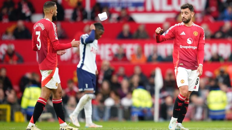 Manchester United's Bruno Fernandes, right, throws a captain armband to Manchester United's Noussair Mazraoui during the English Premier League soccer match between Manchester United and Tottenham Hotspur at Old Trafford stadium in Manchester, England, Sunday, Sept. 29, 2024. (Dave Thompson/AP)