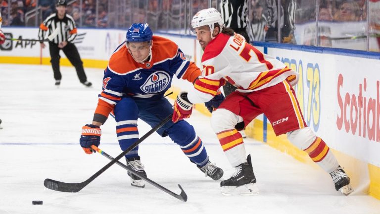 Calgary Flames' Ryan Lomberg (70) and Edmonton Oilers' Travis Dermott (24) battle for the puck during first period NHL action in Edmonton, Sunday, Oct. 13, 2024. (Jason Franson/CP Photo)